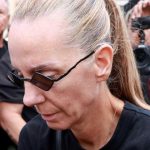 Η Βάσω Μαζωνάκη σκουπίζει με τα χέρια της τη σκόνη πάνω στον τάφο του αδελφού της