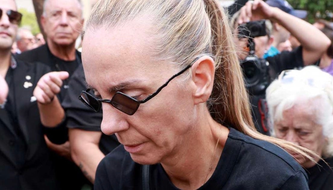 Η Βάσω Μαζωνάκη σκουπίζει με τα χέρια της τη σκόνη πάνω στον τάφο του αδελφού της